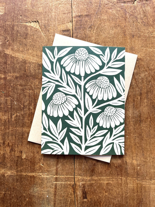 Card with white floral pattern on a green background, placed on a wooden surface